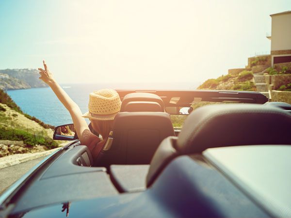 Girl in a convertible driving to the ocean.
