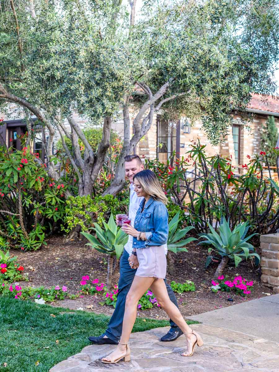 Couple Walking Through The Garden With Drinks.